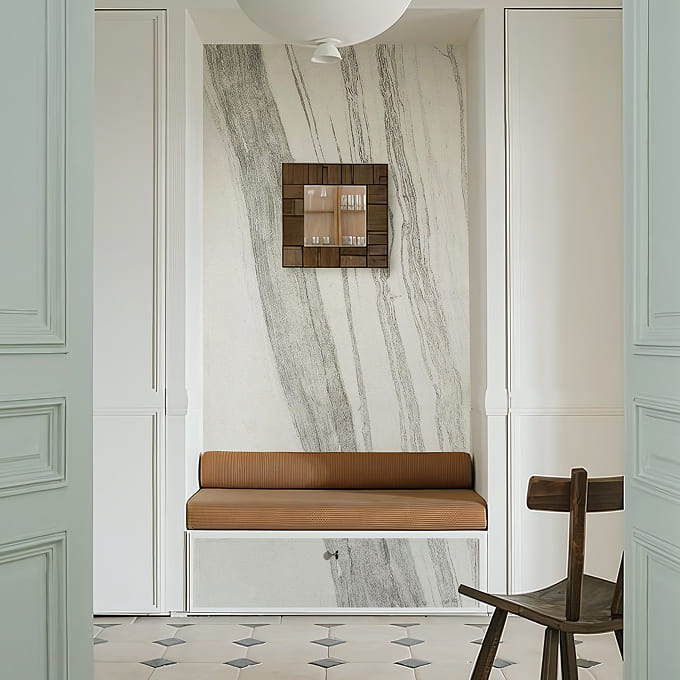 Isvara white marble stone veneer features a wall above an entryway bench.