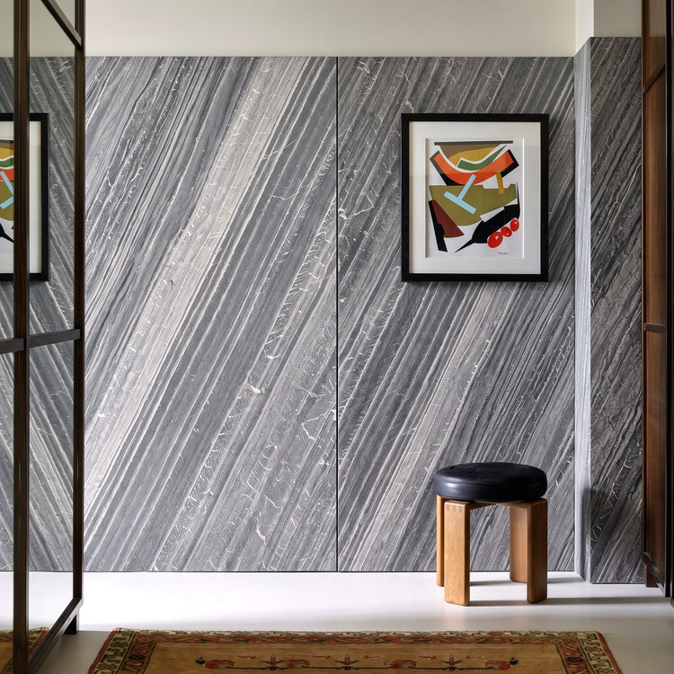 Lanita gray stone veneer feature wall with framed artwork and a wooden stool.